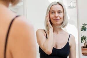 A woman looking in the mirror and smiling after a facelift in Oklahoma