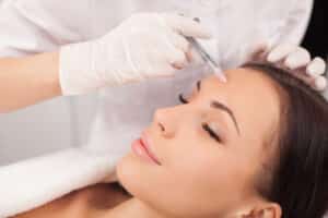 A woman getting a Jeuveau™ injection in her forehead
