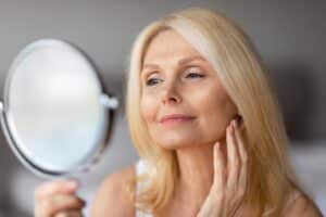 A woman looking in the mirror and admiring the results of a facelift in Norman, OK