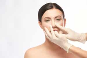 A doctor examining a woman's nose before rhinoplasty in Oklahoma