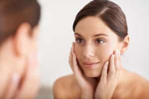 A woman looking in the mirror after a Clear + Brilliant treatment